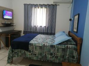 1 dormitorio con 1 cama y ventana con TV en Pousada Pier36, en Peruíbe