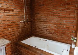 uma banheira branca numa parede de tijolos em Chalé Sol com hidromassagem em meio a natureza em Piçarras