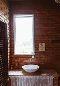 uma casa de banho com um lavatório branco e uma janela em Chalé Sol com hidromassagem em meio a natureza em Piçarras