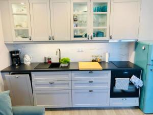 cocina con armarios blancos y encimera negra en Apartament by Karol, en Międzywodzie