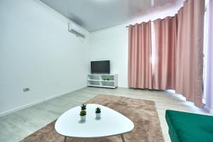 a living room with a white table and a tv at Ana Apartament in Năvodari