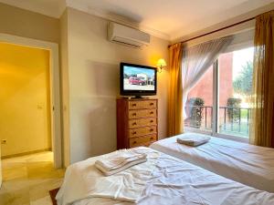 een slaapkamer met een bed, een tv en een raam bij Pool View GOLF FAMILY Ground Floor Terrace with barbecue in Mijas Costa in Mijas