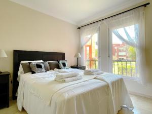 een slaapkamer met een groot wit bed en handdoeken bij Pool View GOLF FAMILY Ground Floor Terrace with barbecue in Mijas Costa in Mijas
