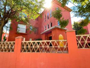 una casa roja con una valla delante en Pool View GOLF FAMILY Ground Floor Terrace with barbecue in Mijas Costa, en Mijas