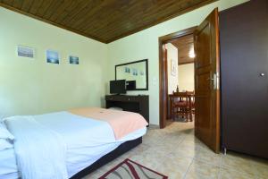 a bedroom with a bed and a television and a door at Haus Platanos Apartments & Bungalows by the Sea in Vourvourou