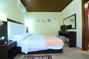 a bedroom with a bed and a desk and a television at Haus Platanos Apartments & Bungalows by the Sea in Vourvourou