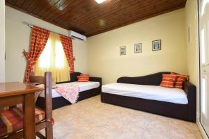 a bedroom with two beds and a desk and a table at Haus Platanos Apartments & Bungalows by the Sea in Vourvourou