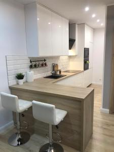 a kitchen with a wooden counter and white cabinets at Apartament Nowodworska in Elblag