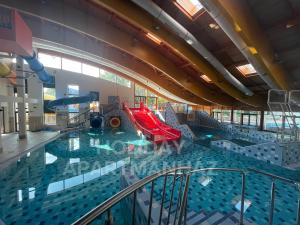 una gran piscina con un tobogán en un edificio en Holiday Apartmanház, en Harkány