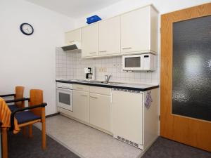 een kleine keuken met witte kasten en een magnetron bij Apartment, Dornumersiel in Dornumersiel