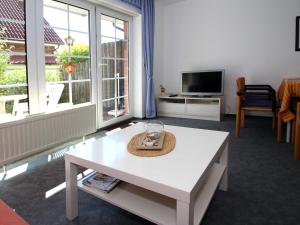 een woonkamer met een witte salontafel en een tv bij Apartment, Dornumersiel in Dornumersiel