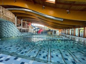 a large swimming pool in a large building at Holiday Apartmanház in Harkány