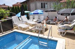 a pool with chairs and umbrellas and people sitting at Family Hotel Dalia in Velingrad