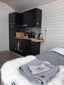 a kitchen with black cabinets and a bed in a room at Willa Rauha 1B in Lumijoki