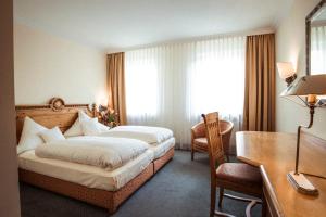 a hotel room with a bed and a desk at Hotel Limmerhof in Taufkirchen