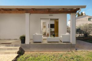 a house with two white chairs on a patio at Apartments Elena Tia in Medulin