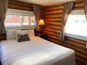 ein Schlafzimmer mit einem weißen Bett in einem Zimmer mit Holzwänden in der Unterkunft Sportsman's Lodge in Ennis