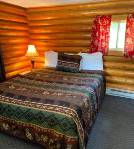 ein Schlafzimmer mit einem Bett in einem Holzzimmer in der Unterkunft Sportsman's Lodge in Ennis