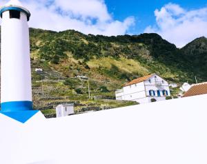 a white lighthouse with a mountain in the background at Alo Baía São Lourenço in Santa Bárbara