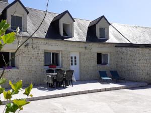 een patio met stoelen en een tafel voor een gebouw bij Au Dom-icile in Monceaux-en-Bessin