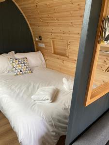 - un lit blanc dans une chambre dotée d'un mur en bois dans l'établissement Robins Nest Glamping Pod with Hot Tub, à Keith