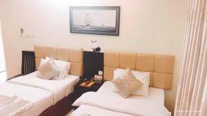 una camera d'albergo con due letti con cuscini bianchi di White Park Boutique Hotel a Chittagong