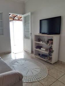 sala de estar con TV de pantalla plana y sofá en Casa aconchegante em Guapé, Lago de Furnas. en Guapé