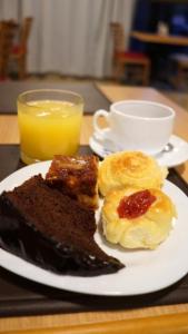 um prato de comida de pequeno-almoço com uma chávena de sumo de laranja em Hotel Golden Park Uberaba em Uberaba