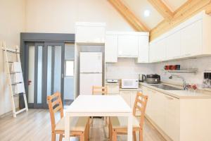 a white kitchen with a white table and chairs at The Viewpoint House in Namhae