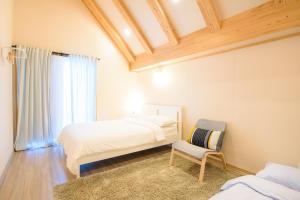 a bedroom with two beds and a chair at The Viewpoint House in Namhae