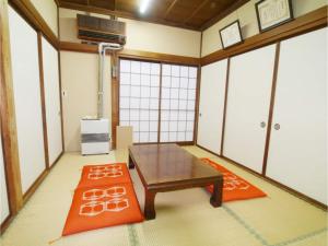 Zimmer mit einem Tisch und zwei orangefarbenen Teppichen in der Unterkunft T-Port hayahoshi - Vacation STAY 12340 in Toyama