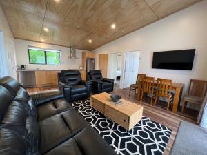 a living room with a leather couch and a table at Country Retreats on Ranzau 7 in Hope