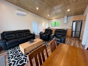 ein Wohnzimmer mit einem schwarzen Ledersofa und einem Tisch in der Unterkunft Country Retreats on Ranzau 8 in Hope