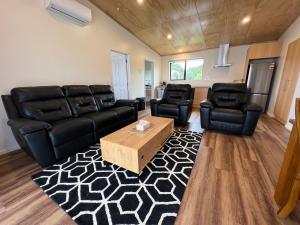 ein Wohnzimmer mit schwarzen Ledermöbeln und einem Couchtisch in der Unterkunft Country Retreats on Ranzau 8 in Hope
