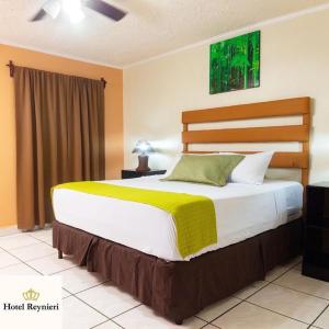 Hotel Reynieri في Comayagüela: غرفة نوم بسرير كبير مع بطانية صفراء