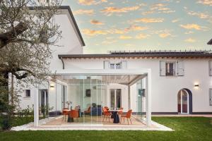 ein weißes Haus mit Glastüren, einem Tisch und Stühlen in der Unterkunft Ca’ Prandini in Maranello