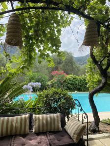 un sofá sentado bajo un árbol junto a una piscina en Bastide Aïna SPA et piscine, en Grasse