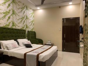 a bedroom with a bed with a green headboard at JK Rooms 126 Parashar Legacy - Opp Railway Station in Nagpur