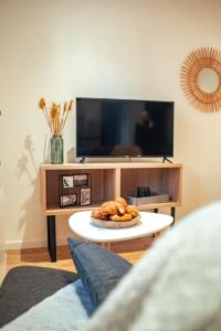 a living room with a tv and a table with a plate of food at Vernon : La Marinière in Vernon +3 photos