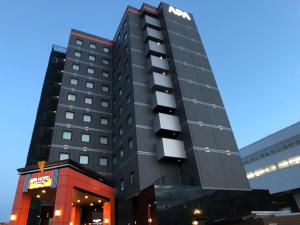 a tall black building with a sign on it at APA Hotel Joetsu Myoko-Ekimae in Joetsu