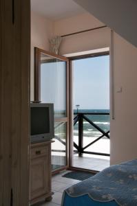a bedroom with a television and a balcony with the ocean at Willa na Wydmie-pokoje z widokiem na morze in Sztutowo
