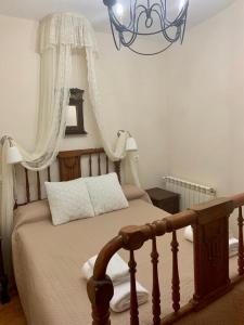 1 dormitorio con cama de madera y lámpara de araña en La Casa Verde en Sanabria de 4 habitaciones y 2 baños, en Cerdillo
