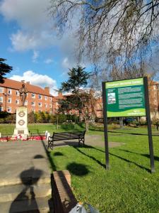 a park with two benches and a sign in the grass at COSY ROOM 2 LONDOn in London