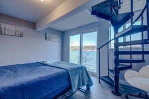 a bedroom with a blue bed and a spiral staircase at Modern Winnipesaukee Lake Front Retreat Siena in Alton