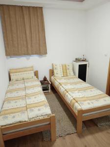 two twin beds in a room with a window at Kapija Dragačeva apartmani in Ovčar Banja