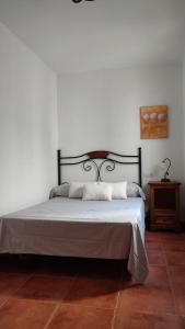 Cama en habitación con pared blanca en Antiguo Consistorio en San Martín de la Vega del Alberche