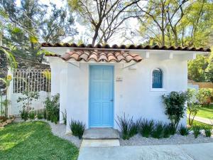une petite maison blanche avec une porte bleue dans l'établissement Hotel Cala Blanca Cuernavaca, à Cuernavaca