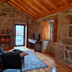 a living room with a piano in a stone wall at Casa da Cantareira in Loriga