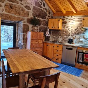 uma cozinha com uma mesa de madeira e uma parede de pedra em Casa da Cantareira em Longa