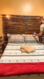 a man is standing next to a large bed at Pousada Aconchego - Suítes Rústicas e Privativas in Lençóis